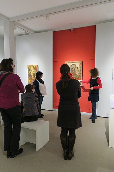 Mehrere Personen stehen vor einer Ikonen im Museum, die von einer Museumsführerin erläutert wird.